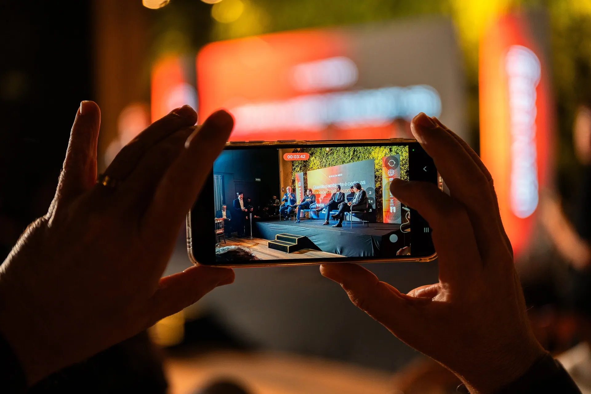 Participante fotografa o palco durante evento da BrainMed